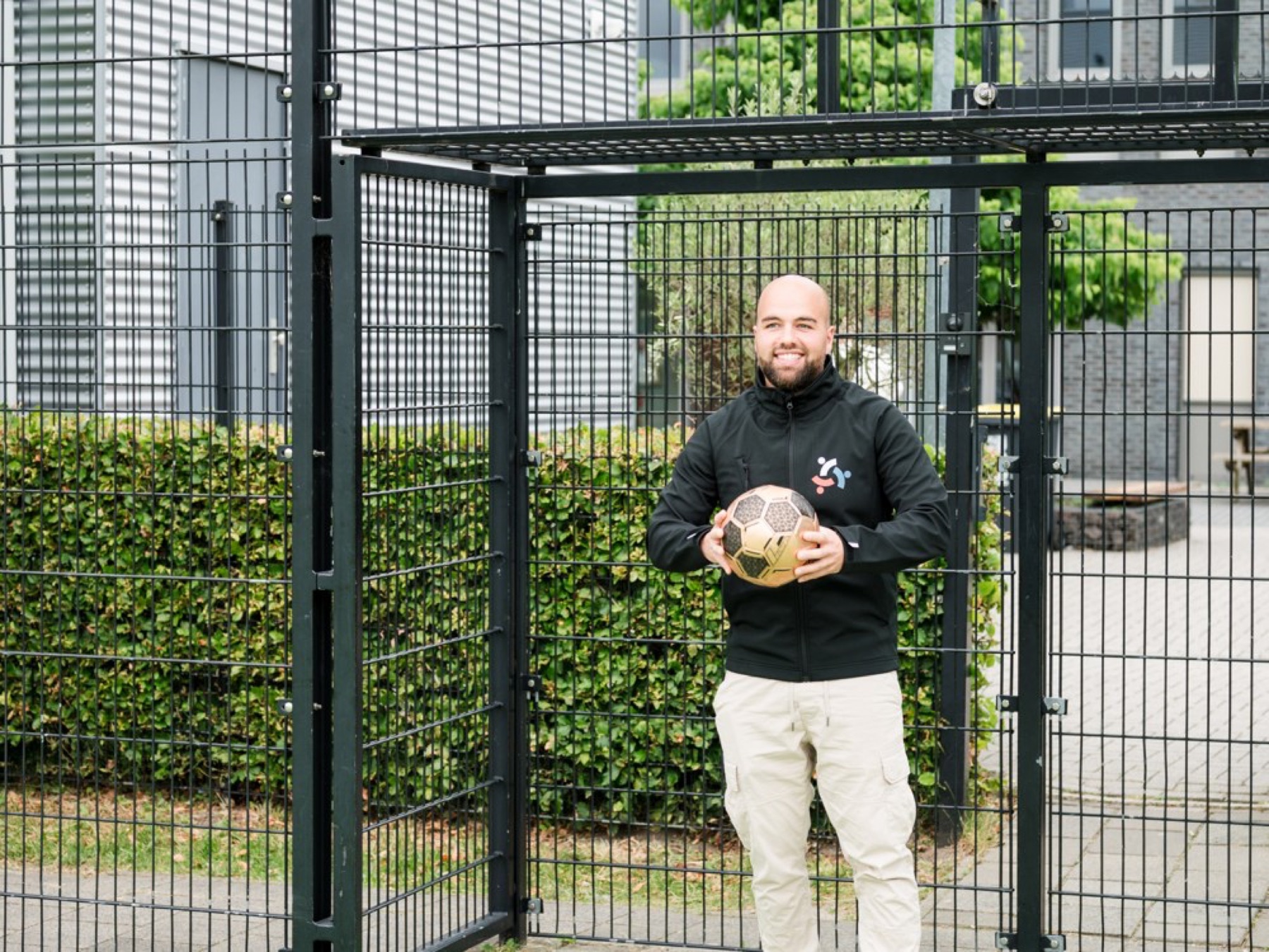 NEXT ST3P-coach met een voetbal bij een sportkooi