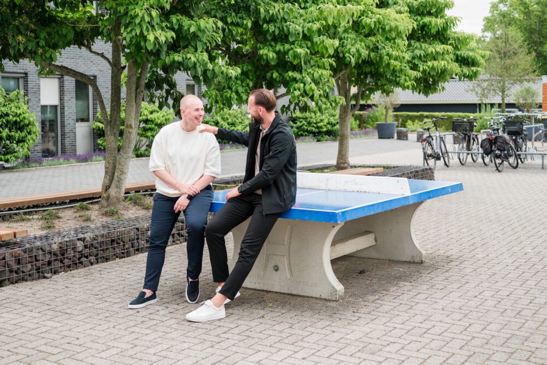 Twee NEXT ST3P-collega’s praten bij een tafeltennistafel